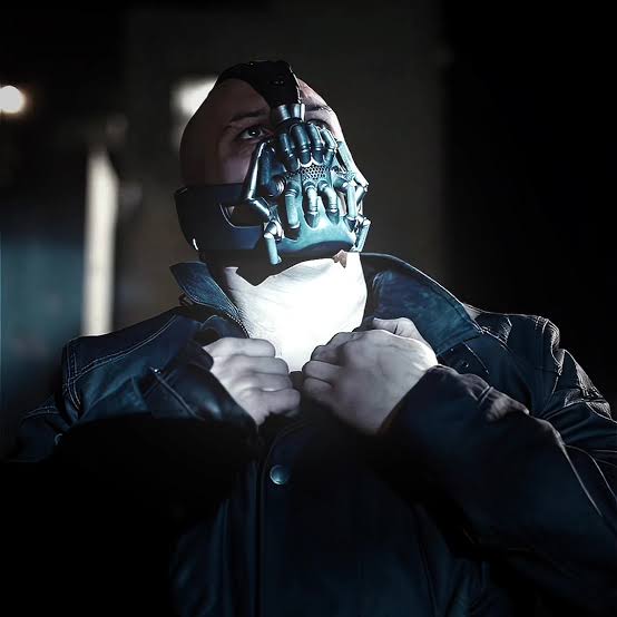 A masked man fastening his coat
